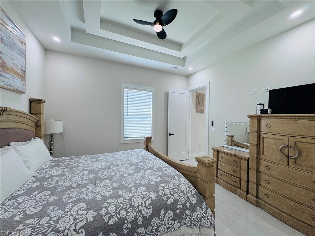 Bedroom featuring a tray ceiling, a ceiling fan, and light tile patterned floors