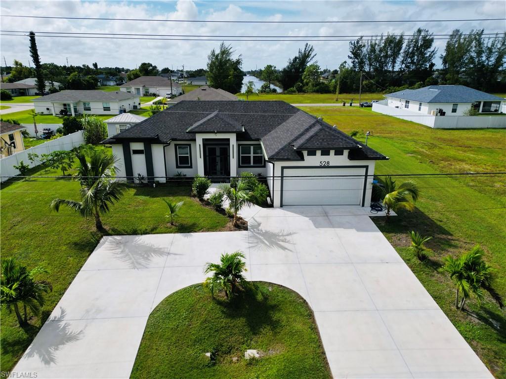 Ranch-style house featuring concrete driveway, stucco siding, a garage, roof with shingles, and a residential view