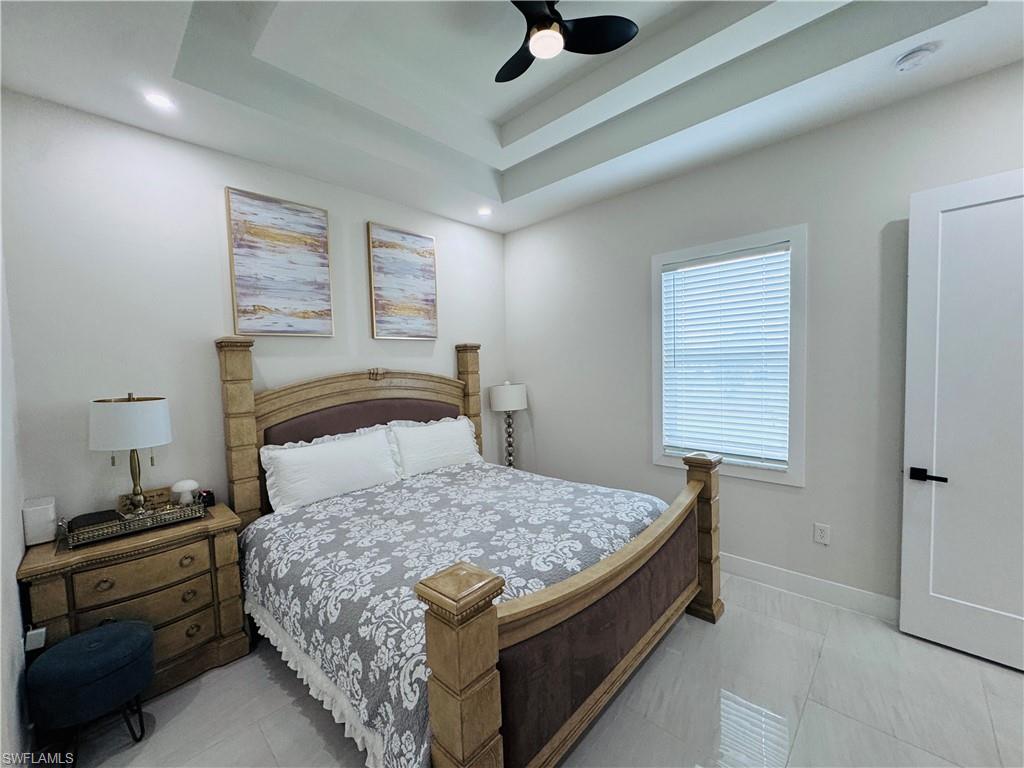 Bedroom featuring light tile patterned flooring, ceiling fan, and a raised ceiling