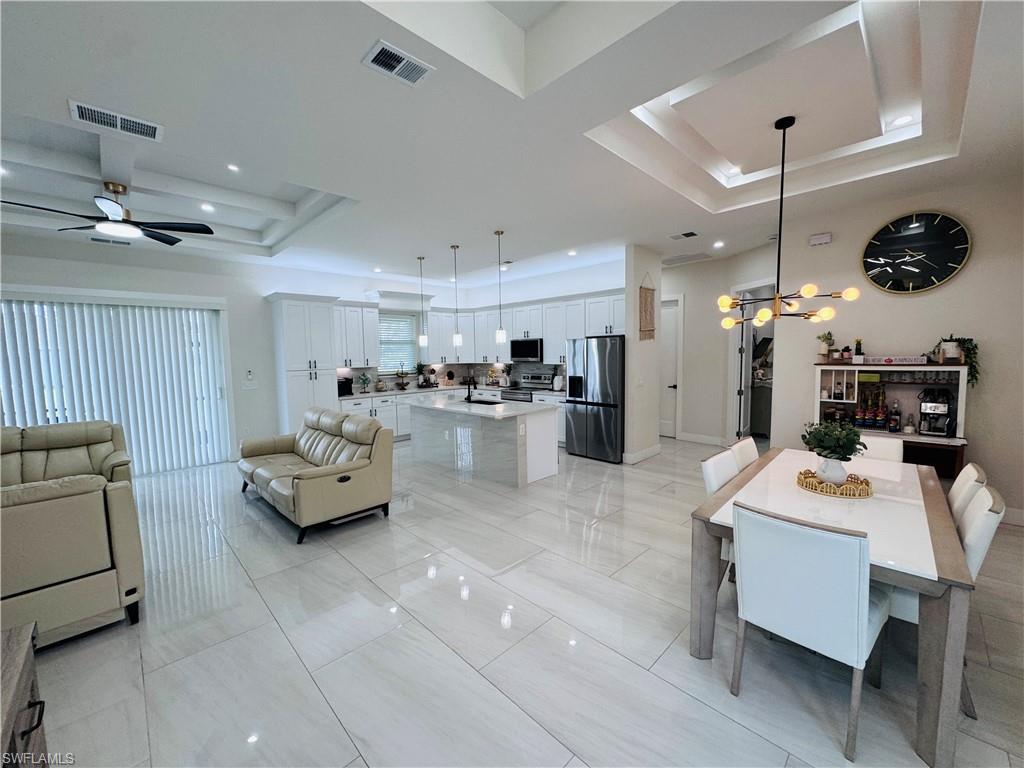 Dining room featuring a raised ceiling, ceiling fan, a chandelier, and recessed lighting