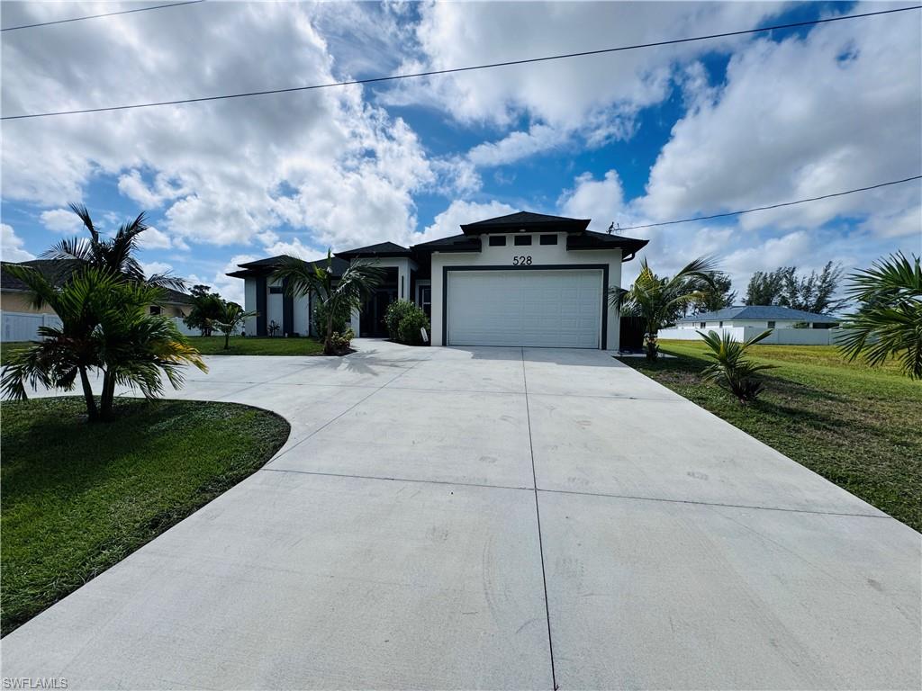 View of front of house with a front lawn, driveway, stucco siding, and an attached garage