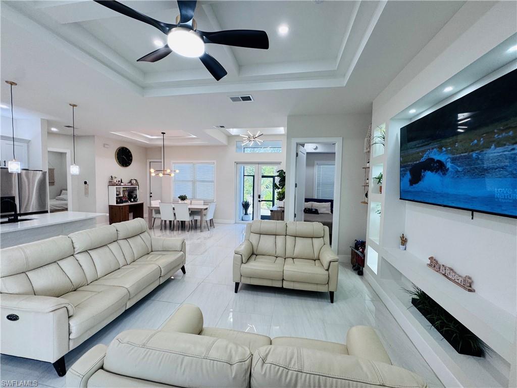 Living area with a raised ceiling, a ceiling fan, and recessed lighting