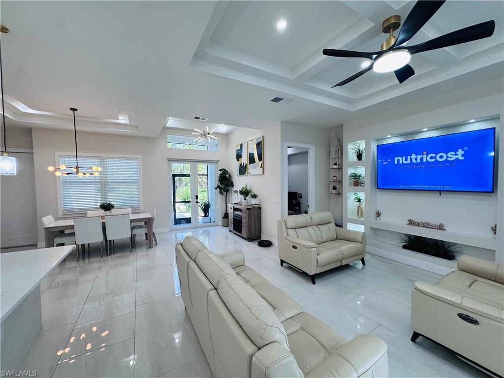 Living area featuring a ceiling fan, a chandelier, french doors, coffered ceiling, and beamed ceiling