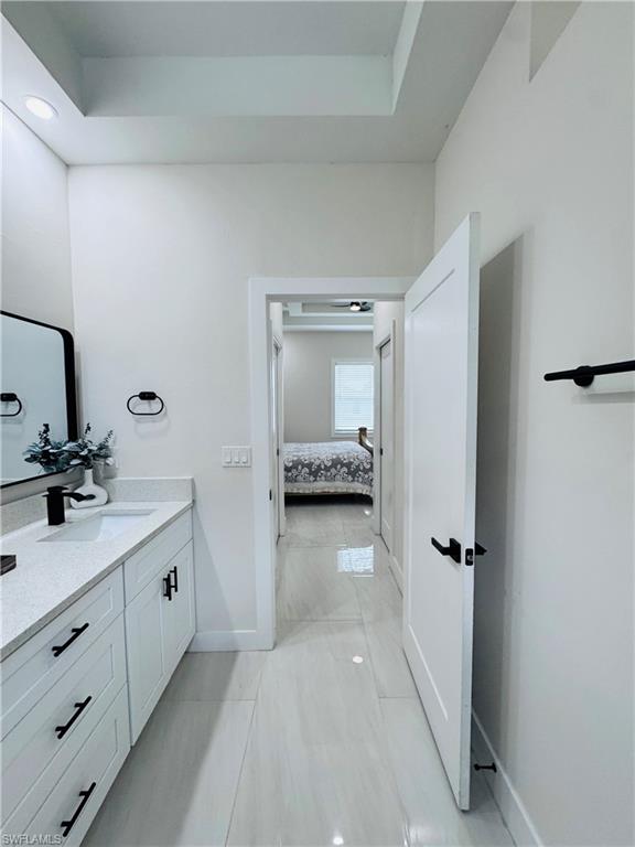 Bathroom with vanity, ensuite bathroom, a tray ceiling, and light tile patterned floors