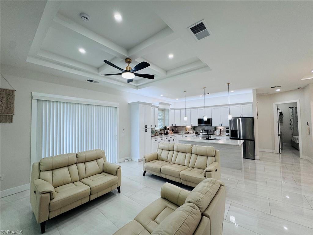Living area with coffered ceiling, beamed ceiling, ceiling fan, recessed lighting, and light tile patterned flooring