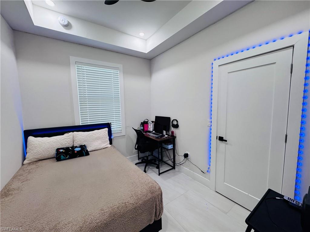 Bedroom featuring a raised ceiling, an office area, and ceiling fan