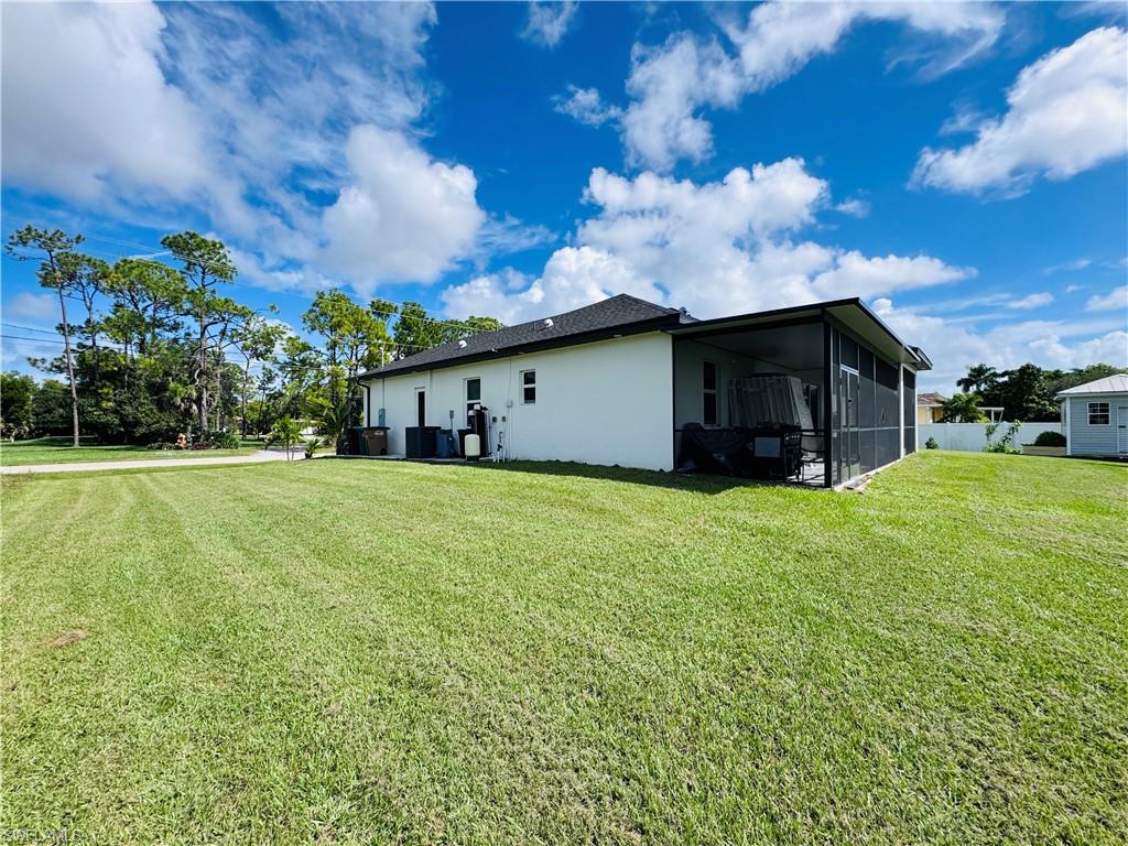 View of side of home featuring a yard, stucco siding, and a sunroom
