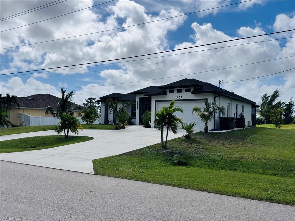 View of front facade featuring a front lawn, driveway, stucco siding, and an attached garage