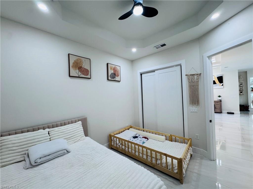 Bedroom with a closet, a raised ceiling, ceiling fan, and recessed lighting