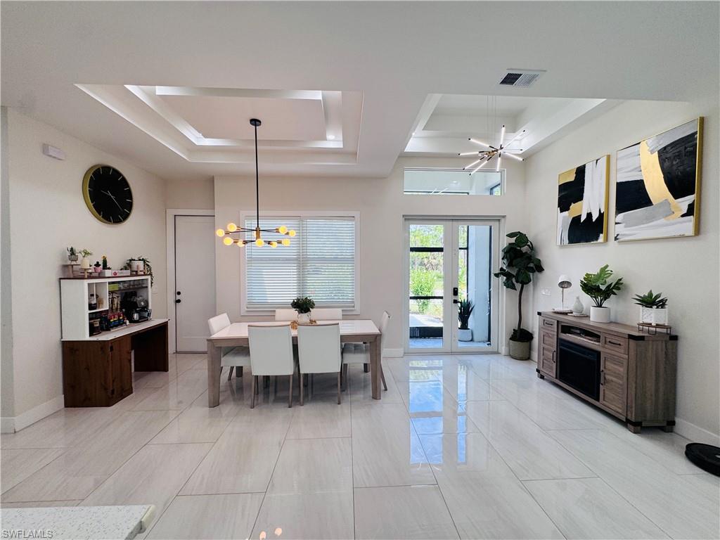 Dining area with a raised ceiling, french doors, and a chandelier