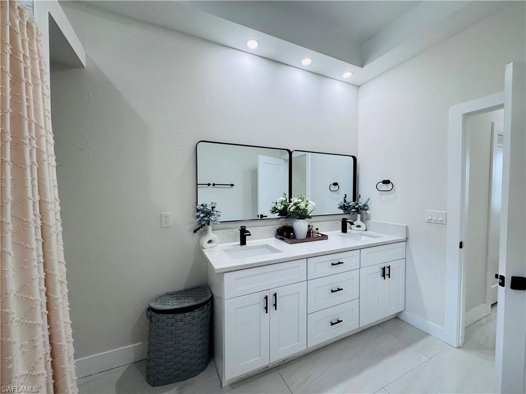 Full bath featuring double vanity, recessed lighting, and light tile patterned floors