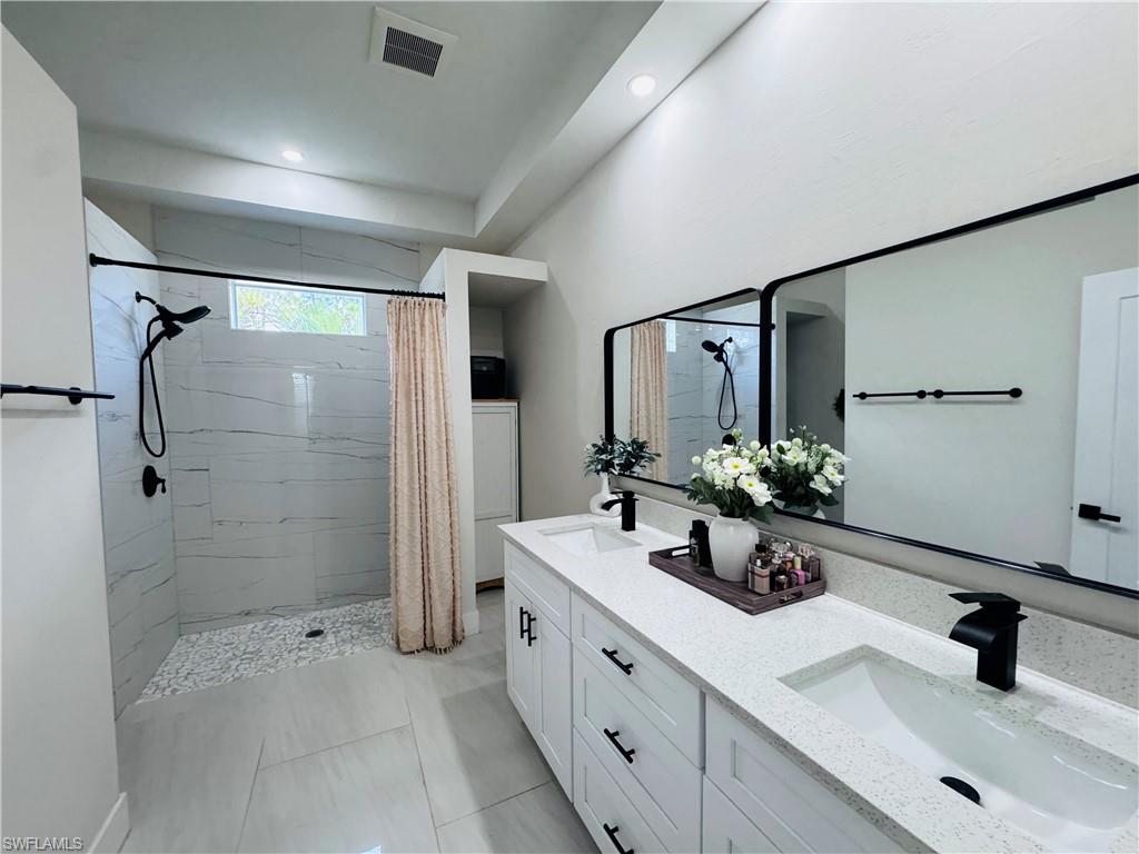Full bathroom featuring double vanity, a stall shower, light tile patterned flooring, and recessed lighting