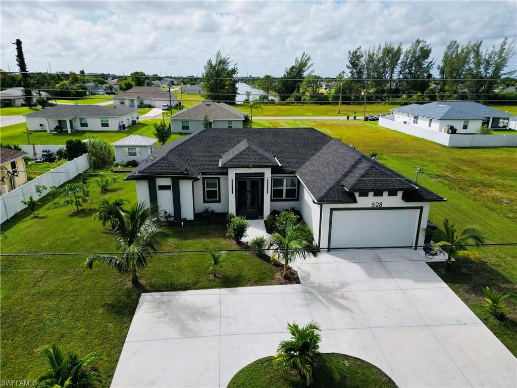View of front of home with a residential view, stucco siding, concrete driveway, a garage, and a shingled roof