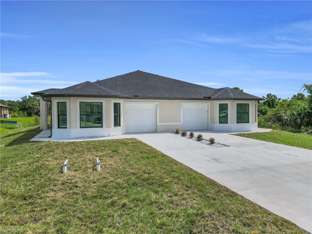 View of front of home featuring stucco siding, driveway, and a front yard