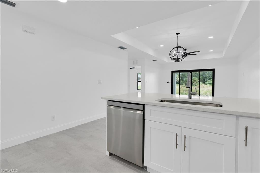 Kitchen with a raised ceiling, recessed lighting, light stone counters, dishwasher, and white cabinetry