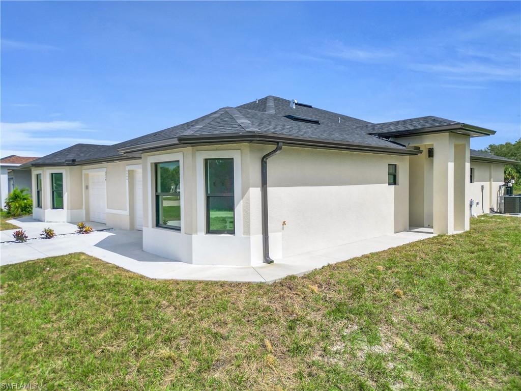 Rear view of property with stucco siding and a lawn