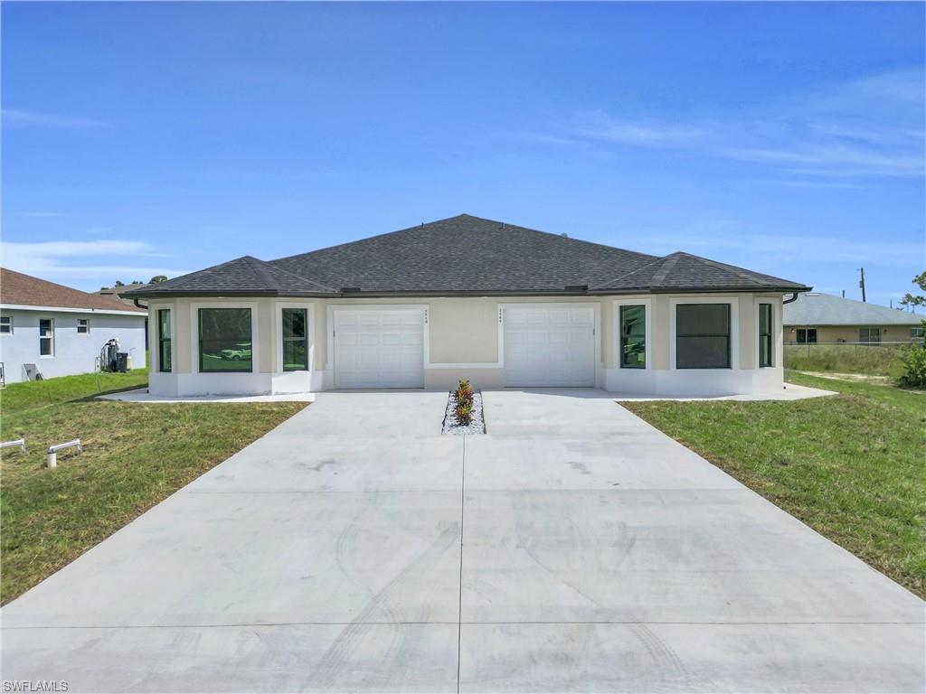 View of front of property featuring a front lawn, stucco siding, driveway, and roof with shingles