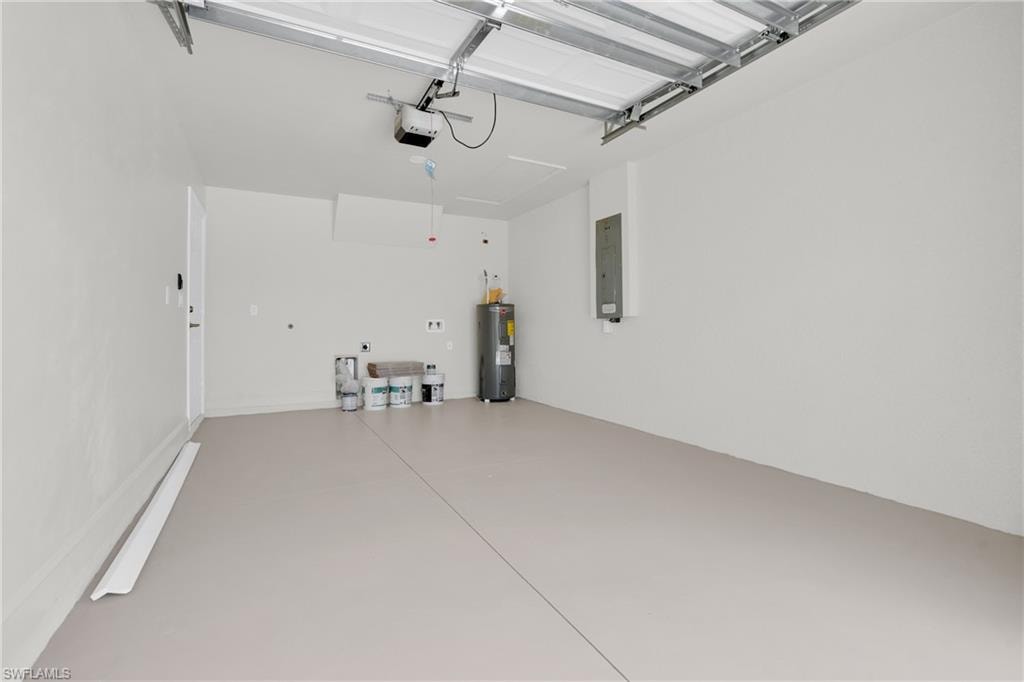 Garage with electric panel, water heater, and a garage door opener