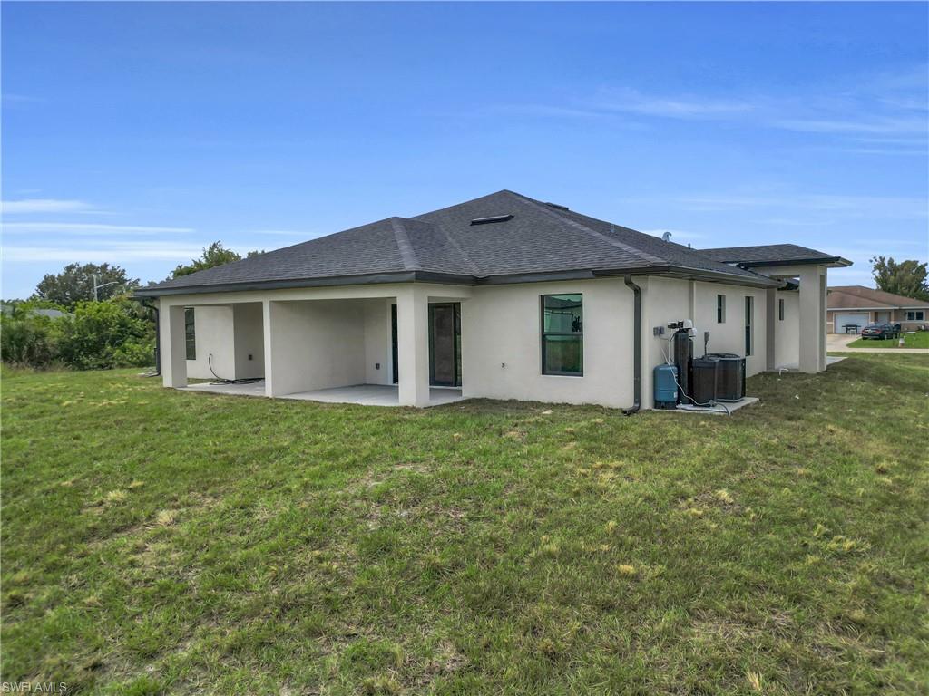 Back of property with stucco siding, a patio area, and a lawn