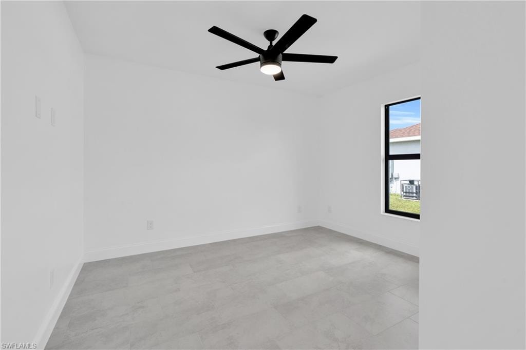 Empty room featuring baseboards and a ceiling fan