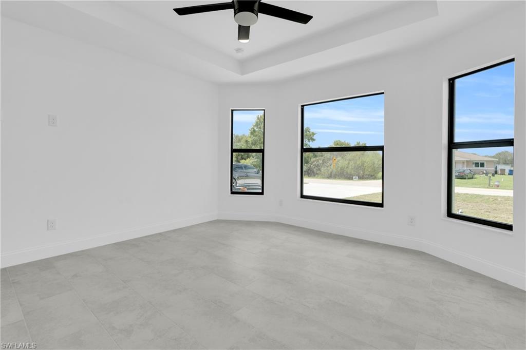 Unfurnished room featuring a raised ceiling and a ceiling fan