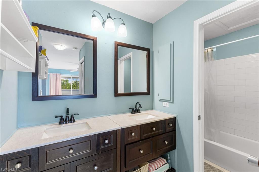 Bathroom featuring shower / bathtub combination with curtain and double vanity