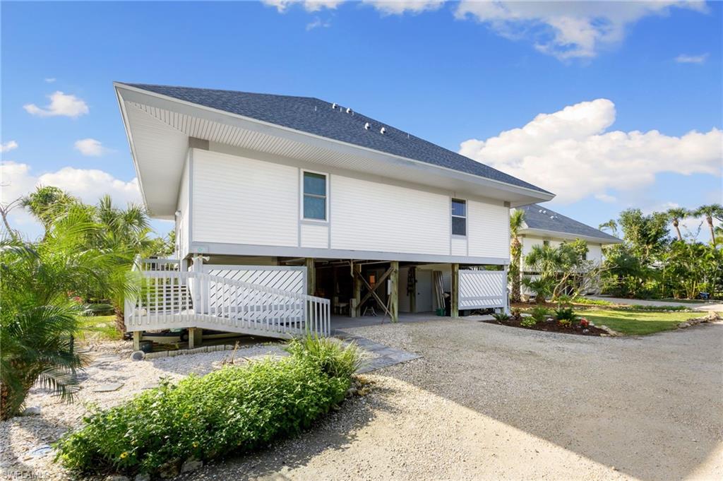 View of property exterior featuring a carport, roof with shingles, driveway, and a wooden deck