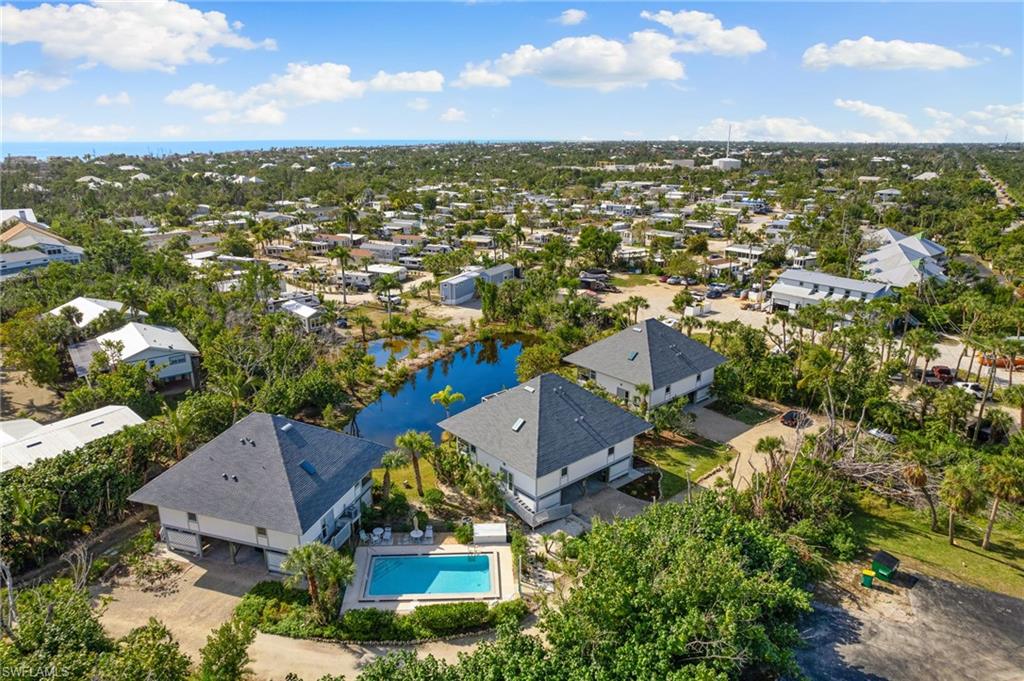 Aerial view of residential area featuring a nearby body of water and a pool