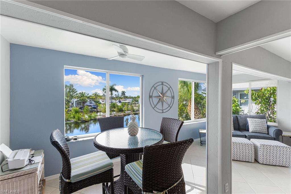 Dining room featuring light tile patterned floors, healthy amount of natural light, a water view, and a ceiling fan