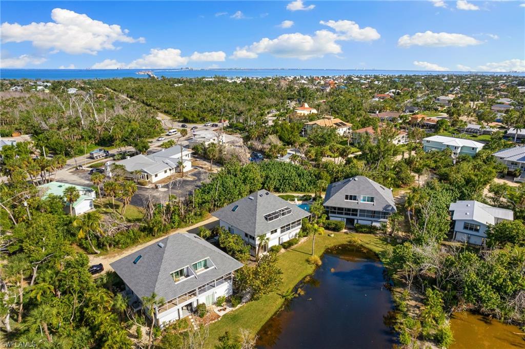 Aerial perspective of suburban area featuring a nearby body of water and a tree filled landscape