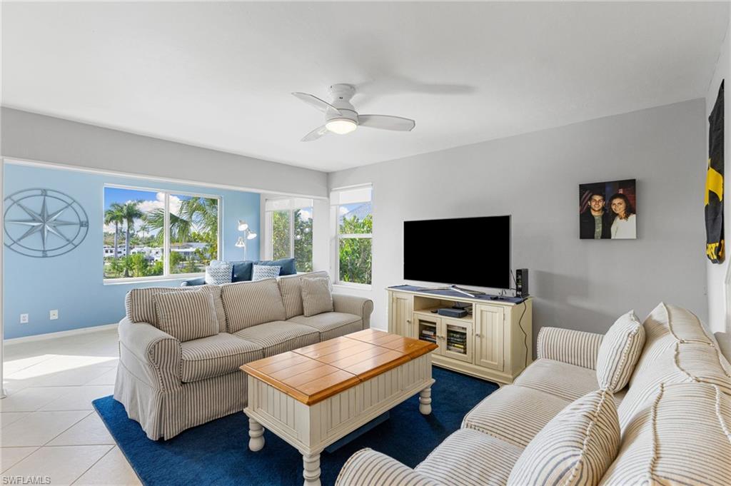 Tiled living room with a ceiling fan and baseboards