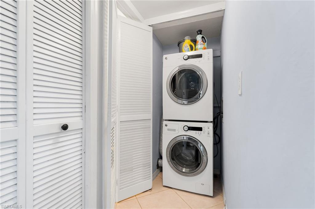 Laundry area with light tile patterned floors and stacked washing machine and dryer
