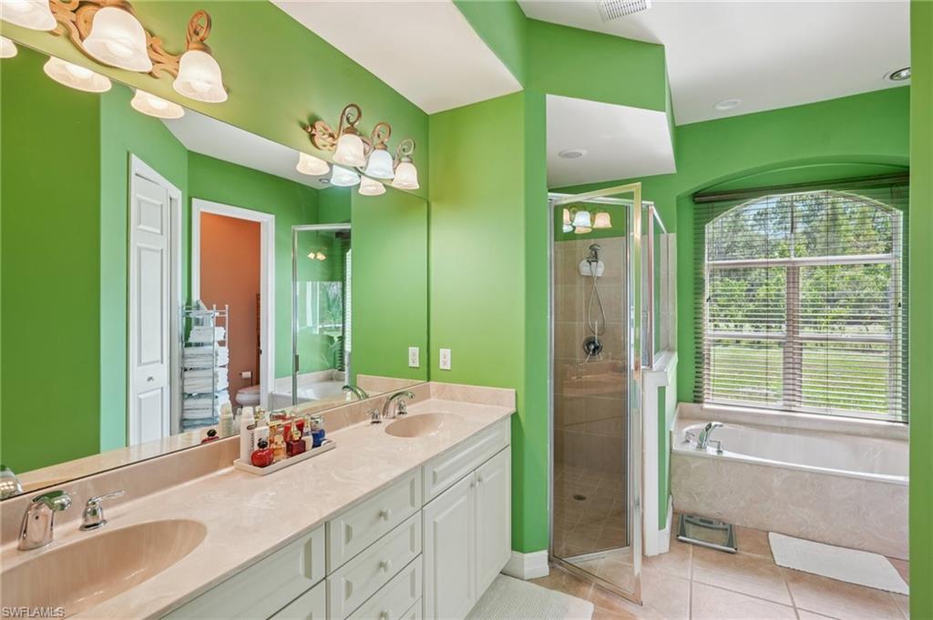 Bathroom with a shower stall, a garden tub, double vanity, and light tile patterned flooring