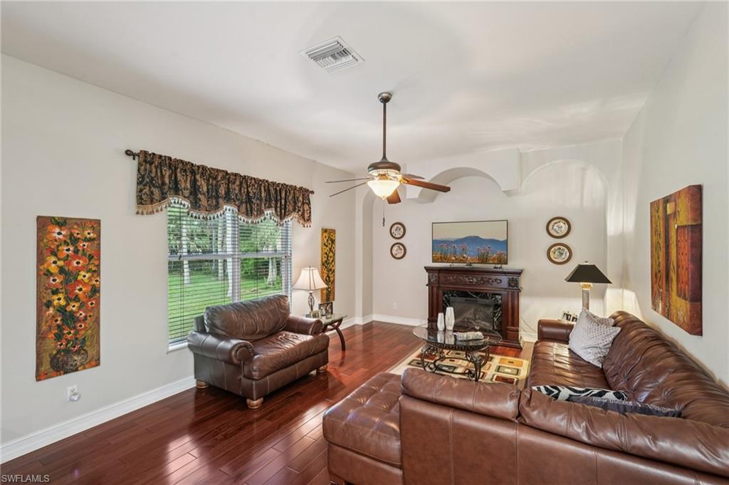 Living room with a glass covered fireplace, hardwood / wood-style flooring, and a ceiling fan