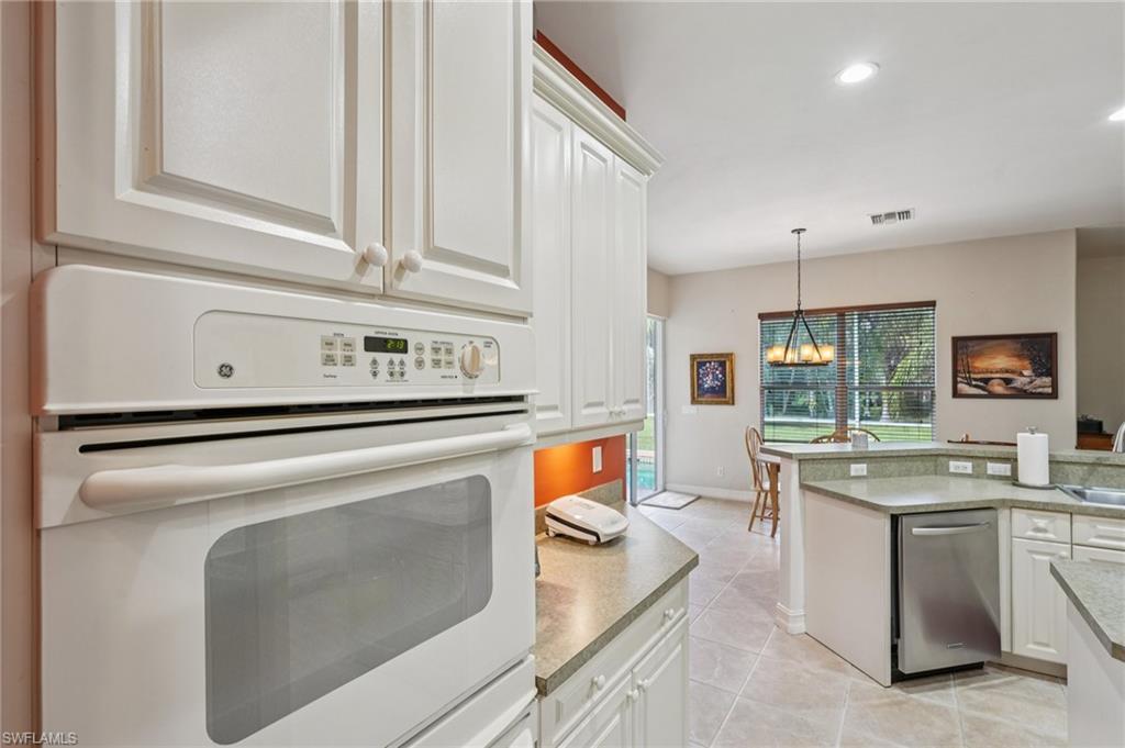 Kitchen with white oven, white cabinets, recessed lighting, light tile patterned floors, and pendant lighting