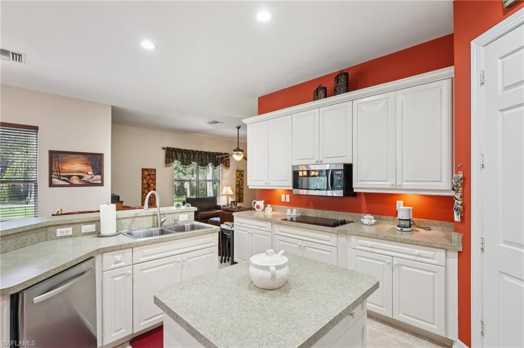 Kitchen featuring a center island with sink, white cabinets, appliances with stainless steel finishes, light countertops, and recessed lighting