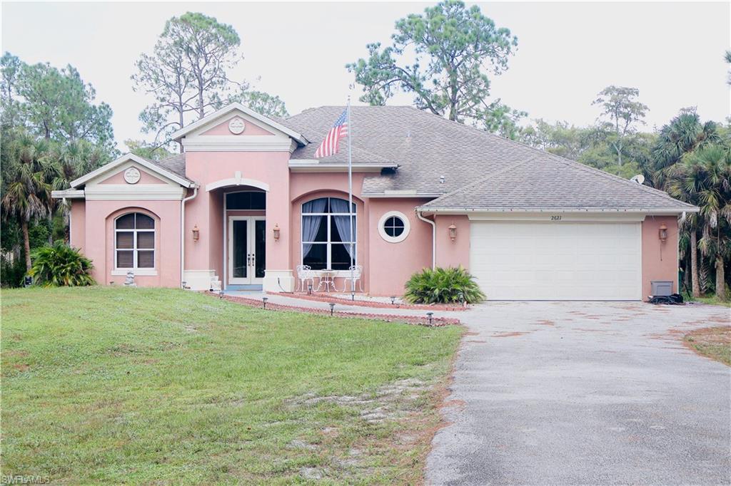 View of front of house with french doors, driveway, stucco siding, a front lawn, and a garage