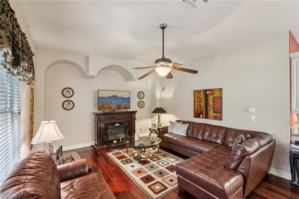 Living area with dark wood-type flooring, ceiling fan, and a glass covered fireplace