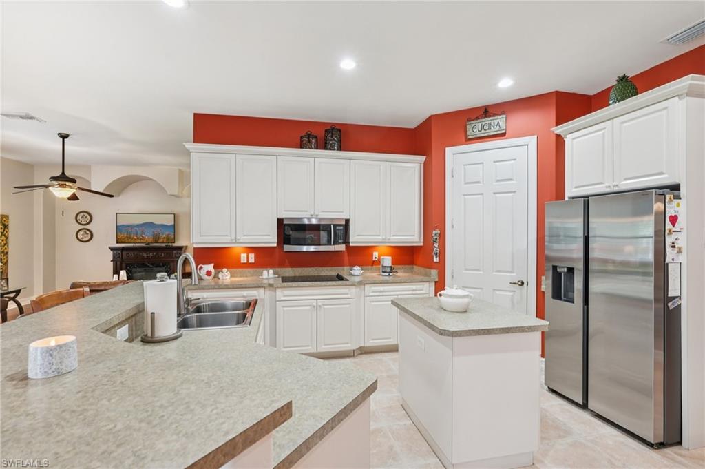Kitchen featuring a kitchen island, stainless steel appliances, white cabinetry, light countertops, and recessed lighting