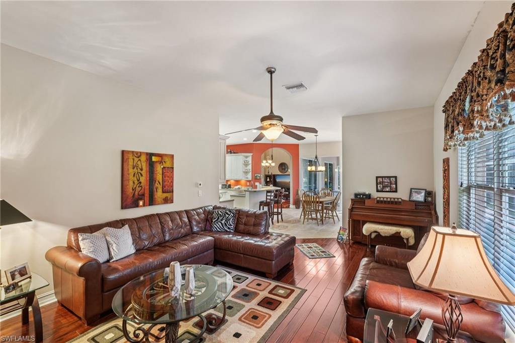 Living area featuring dark wood finished floors, ceiling fan, and a chandelier