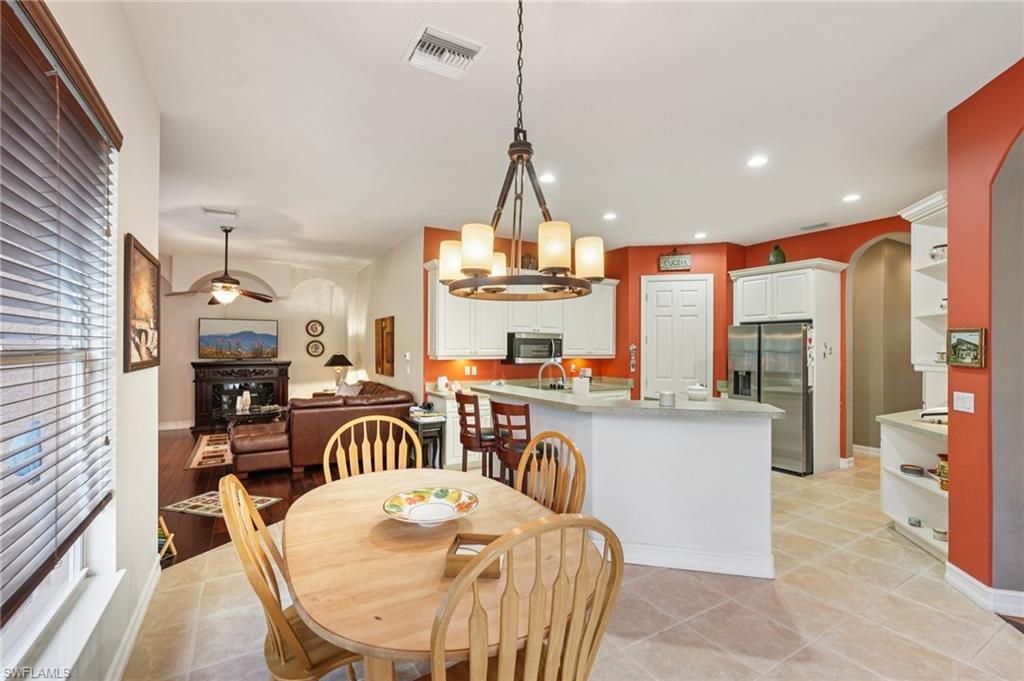 Dining space featuring a chandelier, arched walkways, recessed lighting, light tile patterned floors, and a ceiling fan