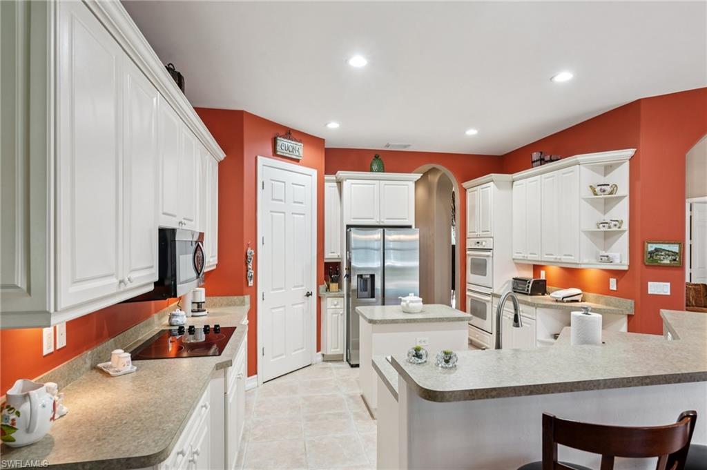 Kitchen featuring white cabinets, open shelves, recessed lighting, arched walkways, and a kitchen island
