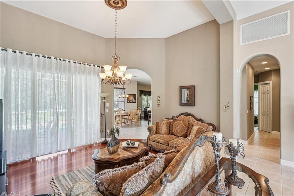 Living room with arched walkways, a high ceiling, a chandelier, and light tile patterned floors