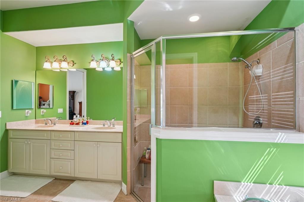 Bathroom featuring a shower stall, double vanity, and light tile patterned floors