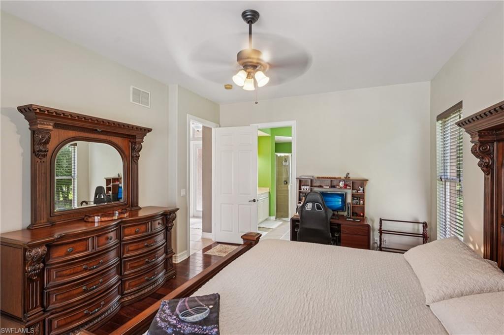 Bedroom with multiple windows, dark wood finished floors, ceiling fan, and ensuite bath