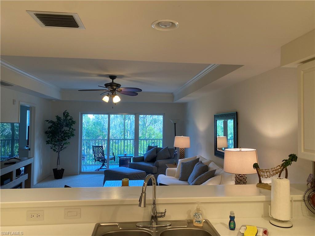 Kitchen with ornamental molding, a ceiling fan, a raised ceiling, open floor plan, and light countertops