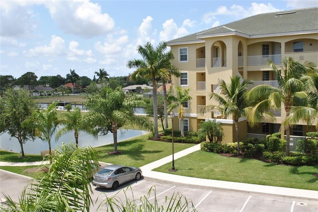 View of home's community with a lawn, a water view, and uncovered parking