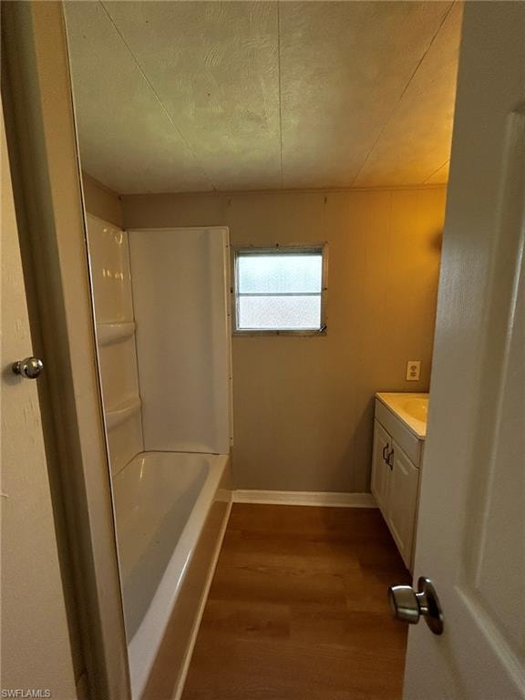 Full bathroom featuring dark wood-style floors, vanity, shower / bathtub combination, and a textured ceiling