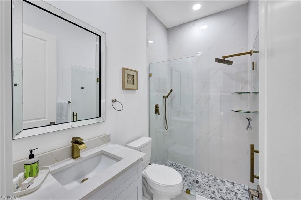 Full bath featuring a marble finish shower, vanity, and recessed lighting