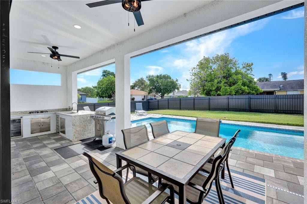 Fenced backyard featuring area for grilling, a patio area, a ceiling fan, wine cooler, and outdoor dining area